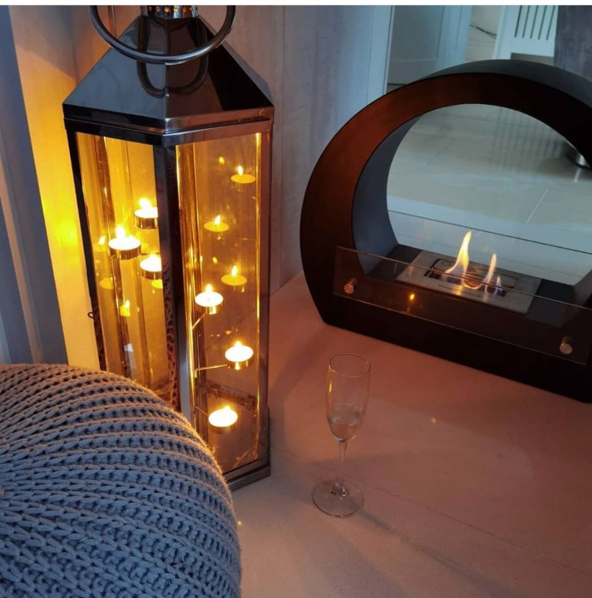 Round black bioethanol fireplace next to a lantern with tea lights inside