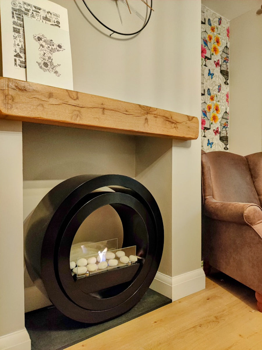 Round black bioethanol fireplace in a beige insert next to a brown chair