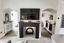 Round black bioethanol fireplace positioned in the centre of a living room under a large TV