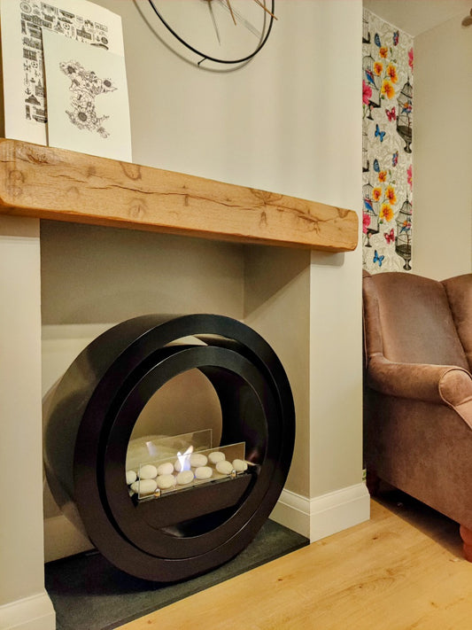 Round black bioethanol fireplace in a beige insert next to a brown chair