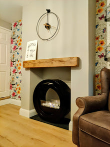 Round black bioethanol fireplace in a beige insert with a contemporary clock above