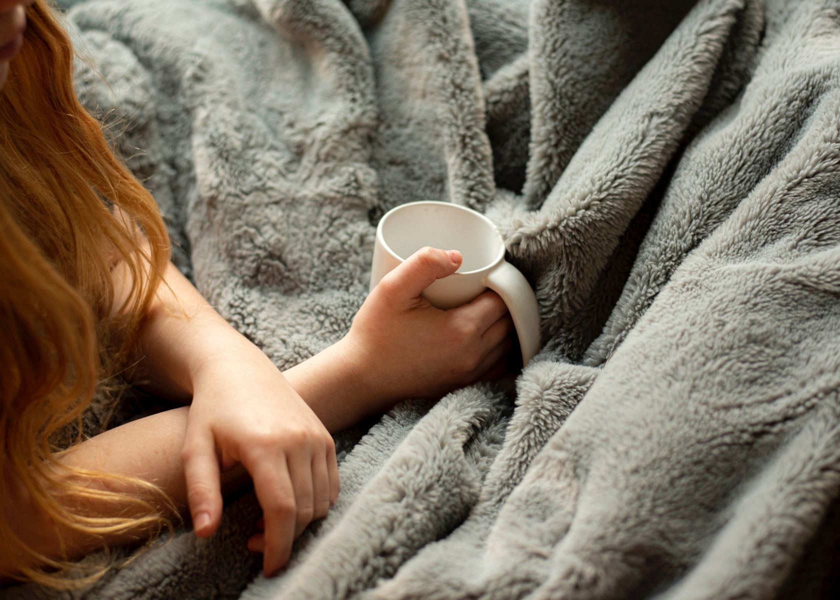 Woman having a hot beverage over a warm blanket