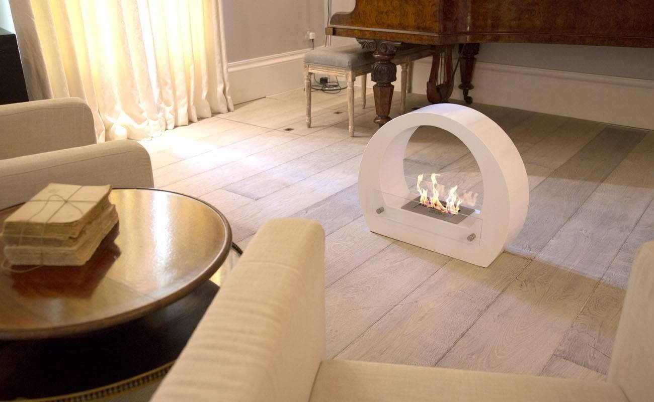 White bioethanol fireplace in the living with chairs and a piano