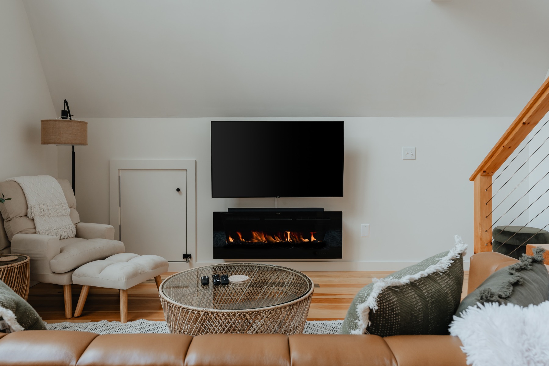 Small living room with white chair and media wall with fireplace