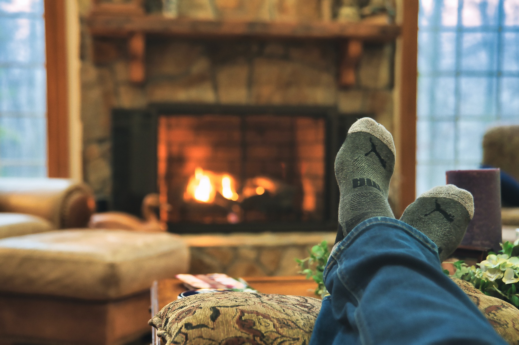 Person lying down with their feet up across a fireplace