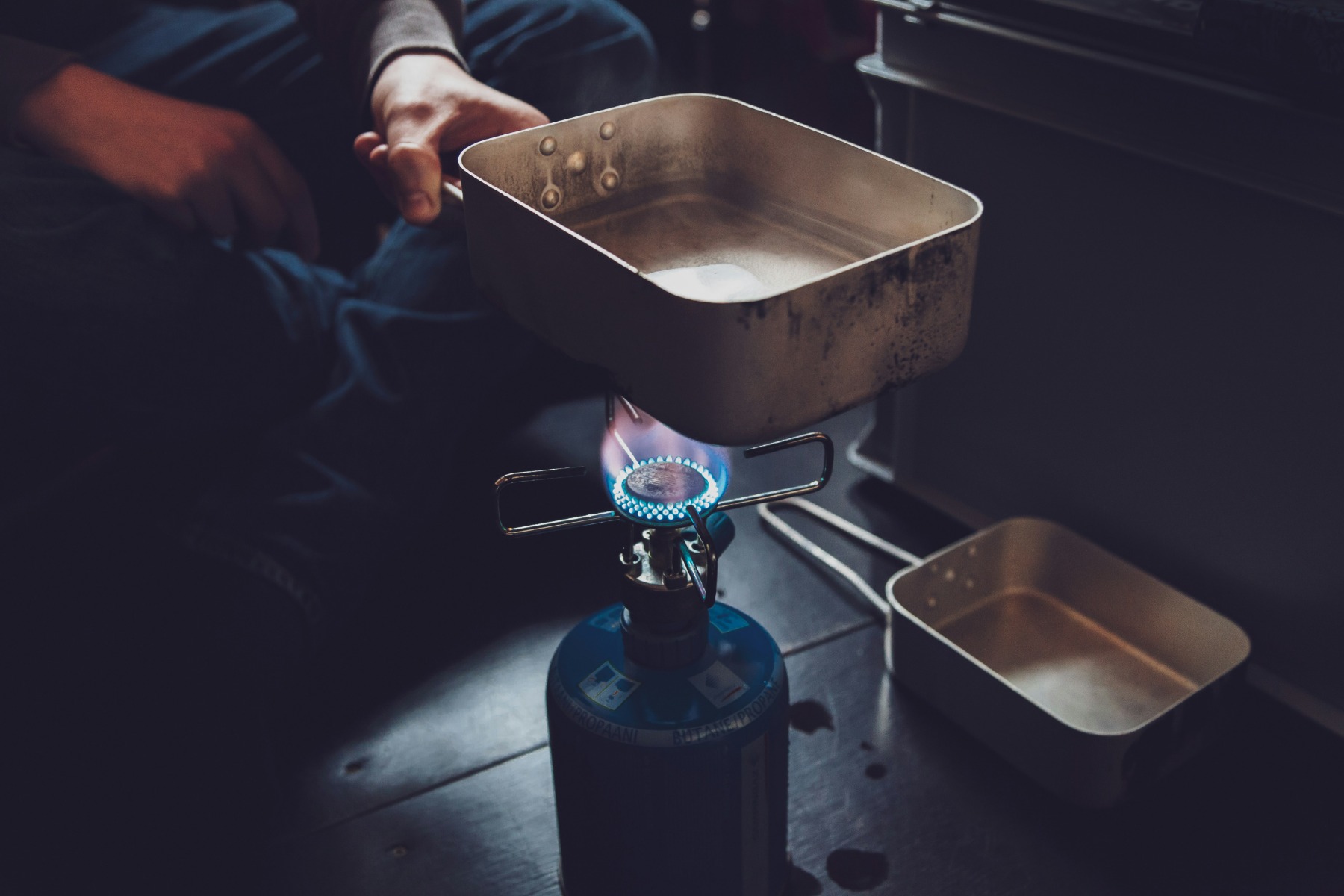 Person heating water using a blue propane tank