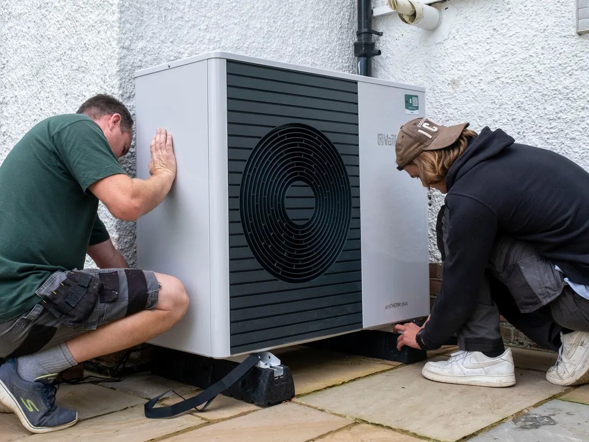 Two men working on an air-source heat pump