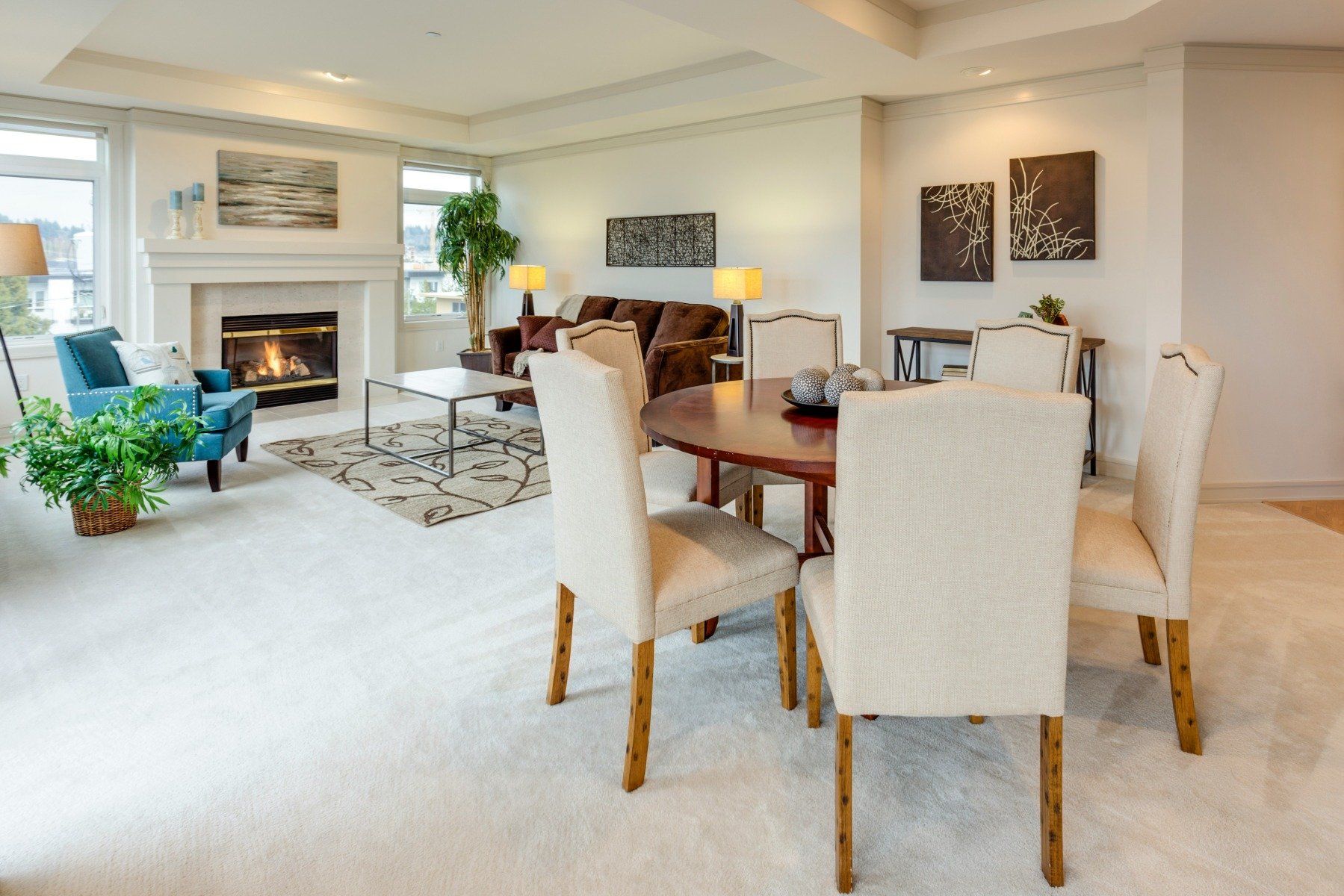 White fireplace in a large living room with beige chairs