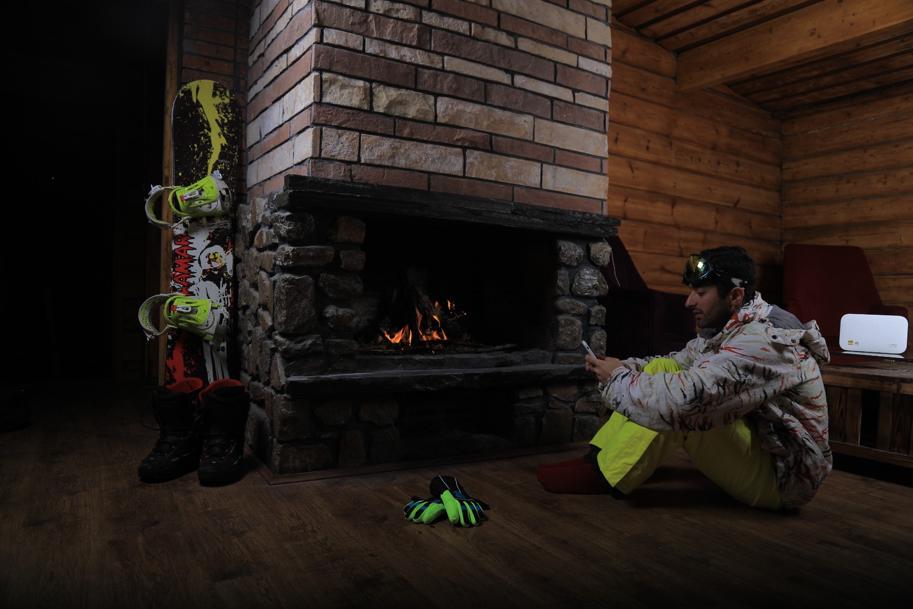 Man in snowboarding gear sitting next to open fireplace
