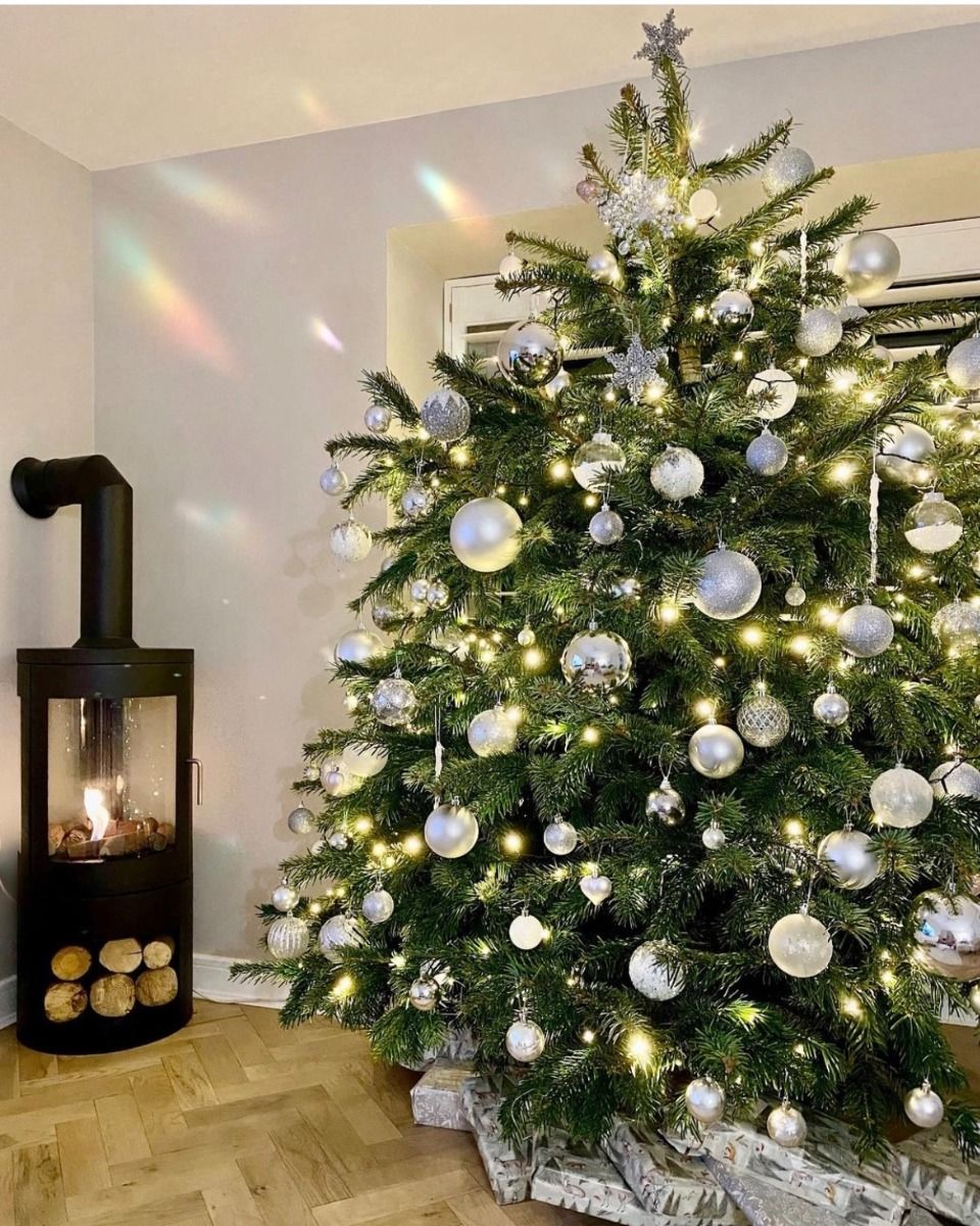 Black bioethanol fireplace next to a large Christmas tree with baubles
