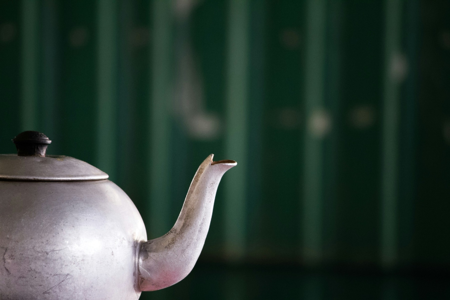 Metal kettle with a green background