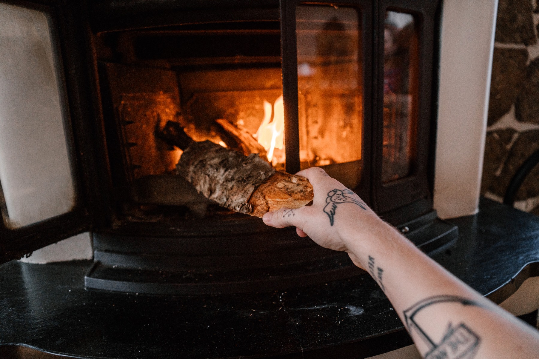 Hand feeding logs to a wood burning fireplace