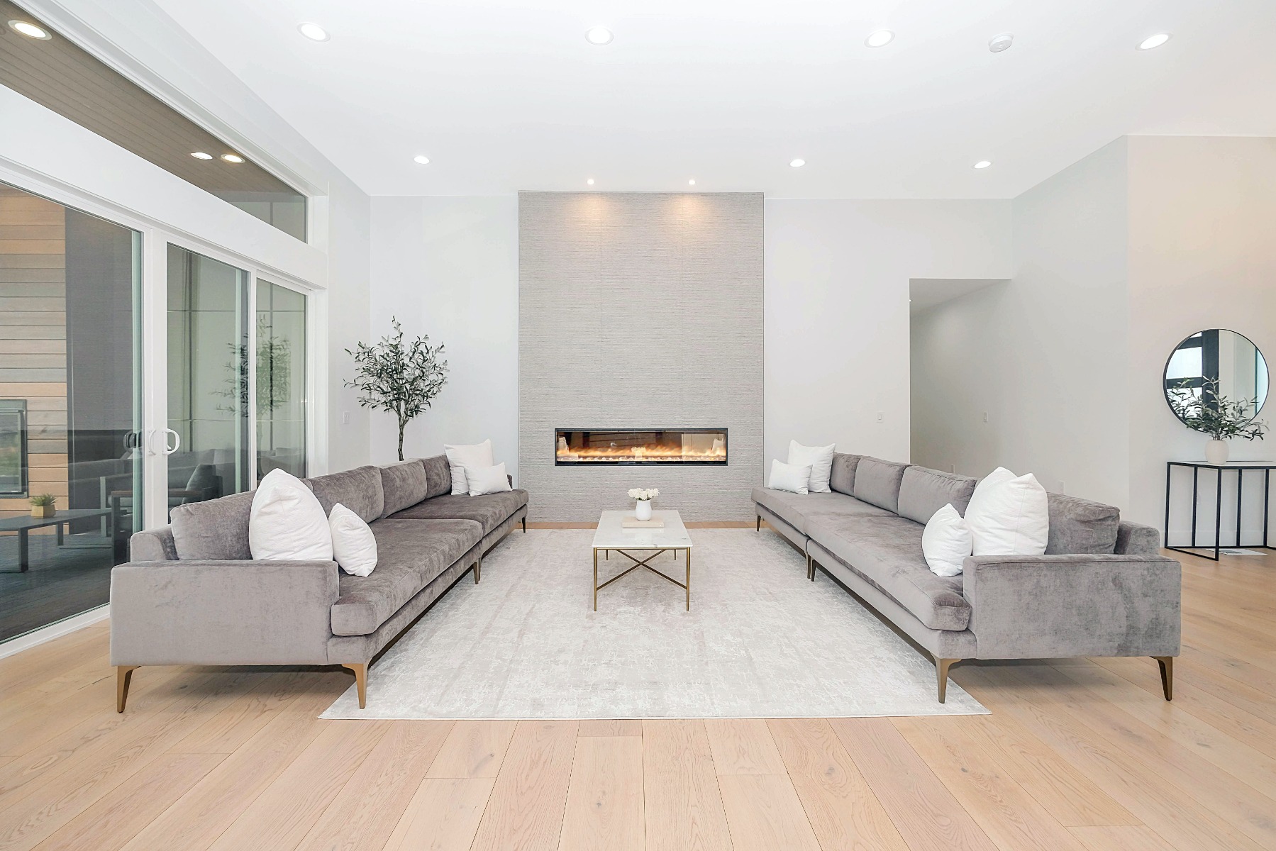 Electric fireplace installed in the centre of a living room with grey sofas on both sides